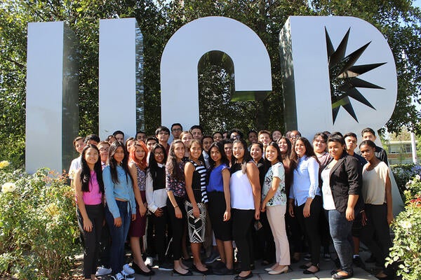 students in front of the UCR signage
